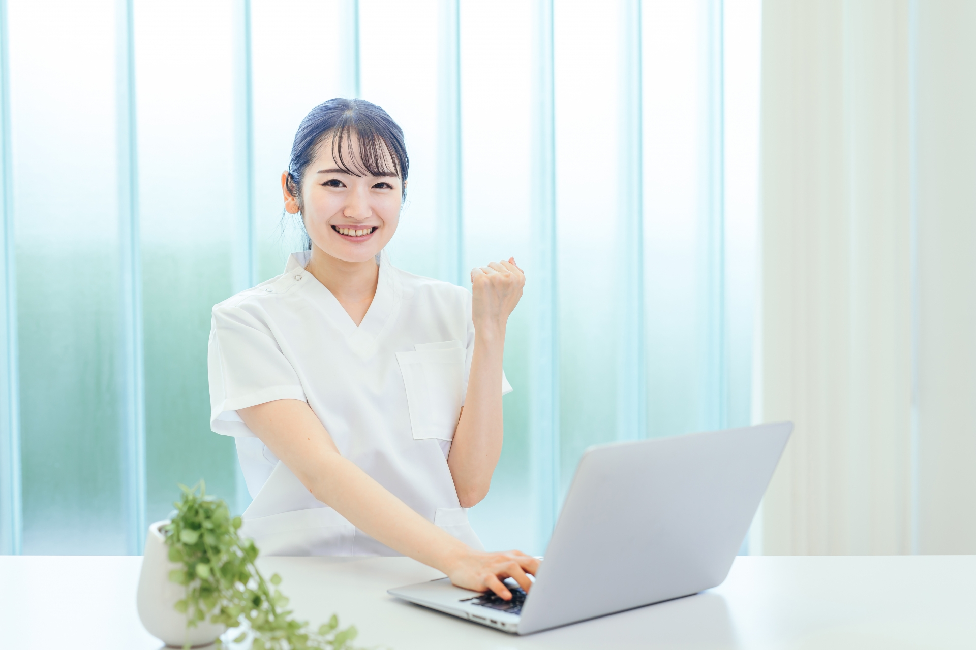 介護と障害福祉専門の税理事務所のイメージ画像_パソコンの前でガッツポーズをする白いスクラブの女性経営者